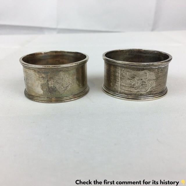 A pair of vintage silver napkin rings, engraved with delicate monograms, were once a staple of elegant dining tables, preserving the formality of meals